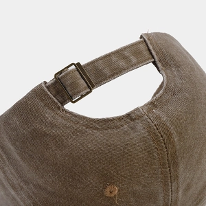 Detail of adjustable metal buckle on back of washed cotton brown baseball cap