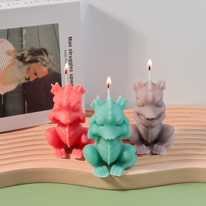 Detailed close-up of cartoon dragon scented candles in red green and grey on wooden tray