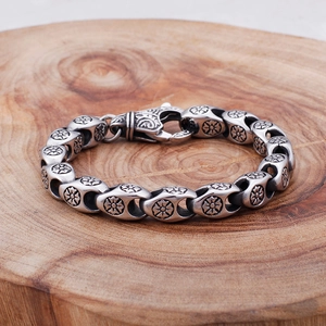 Detailed close-up of retro stainless steel bracelet with floral relief on a wooden base