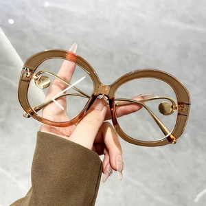 Detail of amber tortoiseshell sunglasses with round metal decorative temple and clear frames