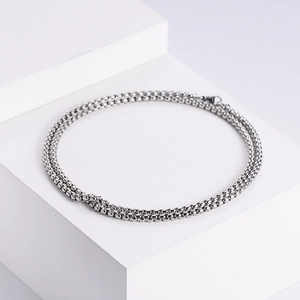 Macro detail of silver stainless steel bead chain on minimalist white geometric props