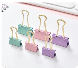 Detail of macaron colored hollow binder clips on a notebook for office organization