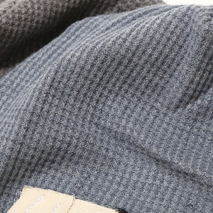 Detailed macro view of heavy waffle knit texture and soft fabric on a gray beanie hat