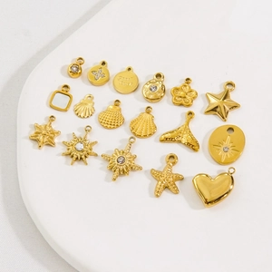 Various 14K gold plated stainless steel charms including star and shell shapes on a white tray