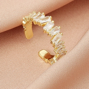 Elegant gold-tone ear cuff featuring rectangular cubic zirconia on peach textured fabric