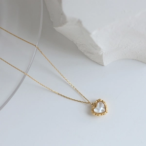 Detailed close-up of heart-shaped shell pendant on a fine gold-plated chain