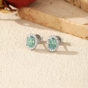 Halo stud earrings with oval mint green gemstone and sparkling white stones on stone texture