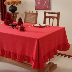 Close-up of red tablecloth with ruffle edge detail on wooden table in elegant setting