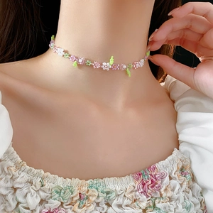Close-up of handmade floral beaded choker with pink and green glass beads on a model