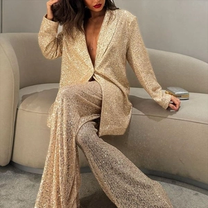 Détail du blazer à paillettes dorées et du pantalon large porté par un mannequin élégant