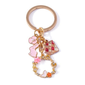 Golden keychain with pink rabbit silhouette and floral wreath pendant on white background