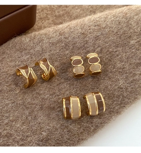 Detailed view of three pairs of brown and cream contrast enamel C-shape stud earrings