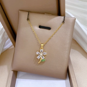 Detailed shot of golden flower pendant necklace with green and white gems in a jewelry box