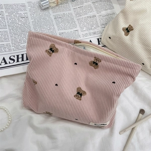 Detailed view of cute bear embroidery on corduroy cosmetic bags with makeup accessories