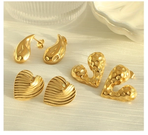 Detail view of gold-plated heart and teardrop earrings with textured finishes
