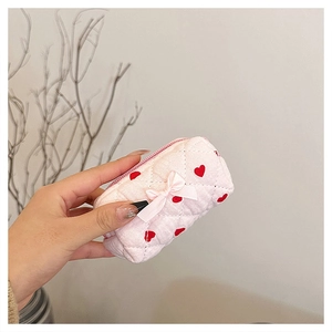 Close-up of pink quilted cotton makeup pouch with red heart patterns and silk bow detail