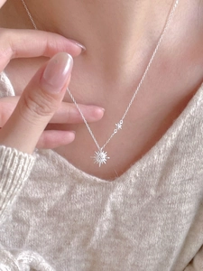 Detail view of 925 sterling silver star pendant necklace worn over a white knit sweater