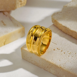 Macro shot of wide gold wavy multi-layer ring displayed on beige natural stone