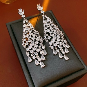 Makroaufnahme von Silber-Quastenohrringen mit Zirkonia-Tropfen auf Lederhintergrund