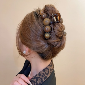 Detail of amber acrylic round bead hair claw clip holding a hairstyle on model