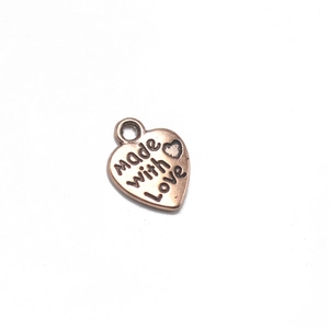 Detalle macro del colgante de corazón 'Made with love' en oro rosa para joyería DIY