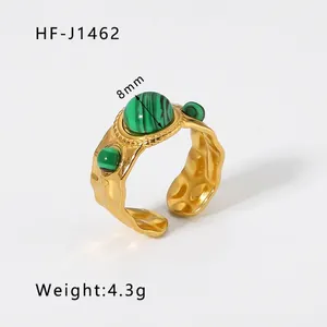 Macro view of 18k gold plated ring with emerald green stones and hammered texture detail