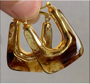 Detail of U-shaped gold metal and amber marble resin geometric earrings for women
