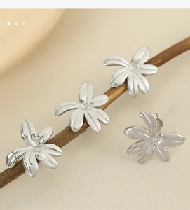 Macro shot of silver floral studs with five-petal design on a natural wooden branch