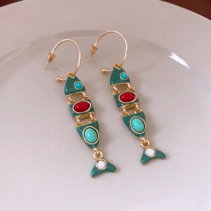 Detailed shot of vintage fish tassel earrings with green enamel and colorful gemstones