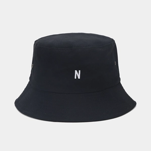Détail de la broderie N blanche et des œillets sur un chapeau bob en coton noir