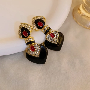Detail of vintage heart-shaped earrings with black enamel and sparkling red rhinestones