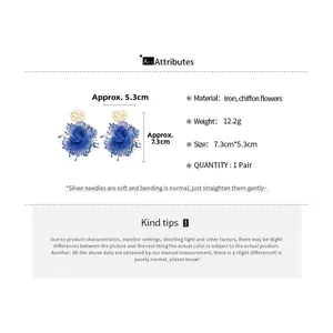 Detailed view of blue chiffon flower earrings with silver needles and gold base