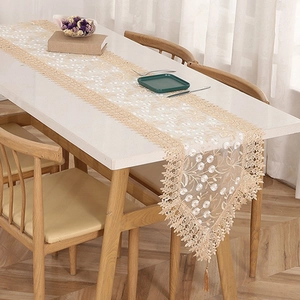 French lace table runner with hollow embroidery and tassel for dining table decor detail view.