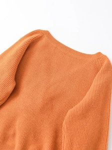 Primo piano del maglione in maglia arancione con scollo rotondo a coste e maniche raglan