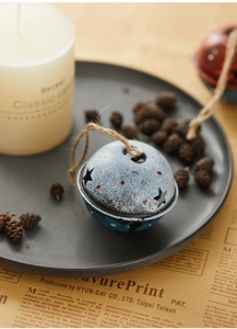 Blue Christmas metal bell with star cutouts and festive speckles in a cozy vintage setting