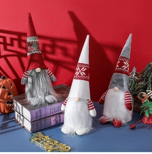 Close-up of three Nordic Christmas gnomes with knit hats and faux fur beards on a shelf
