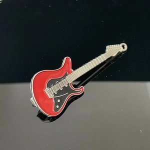Close-up of a Y2K style guitar brooch on black mirror with reflective metallic details