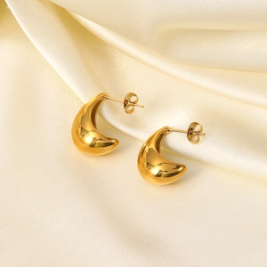 Macro view of gold plated teardrop earrings on white silk with polished mirror finish