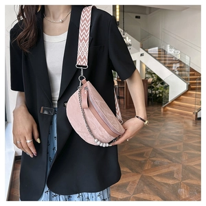 Detail of pink half-moon crossbody bag featuring a textured finish and pearl chain