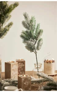 Close-up of frosted PE pine needles in glass vase for cozy Christmas decor