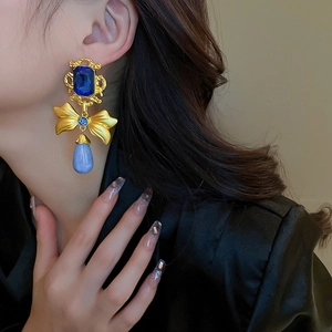 Detail of vintage bow earrings with gold frames, blue gemstones and teardrop beads