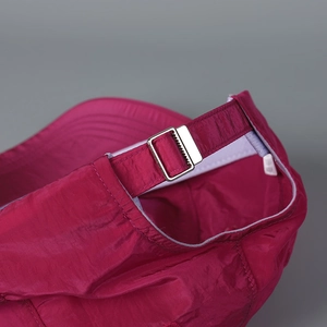 Detail of dark magenta baseball cap with metal buckle and lightweight textured fabric