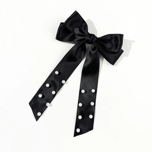 Detail of black satin ribbon bow hair clip with elegant pearl embellishments