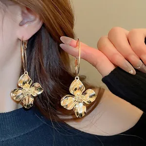 Orecchini a cerchio dorati con petali metallici e stami testurizzati sulla modella