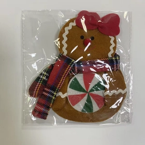 Close-up of gingerbread man cutlery holder in plastic packaging with red bow and scarf