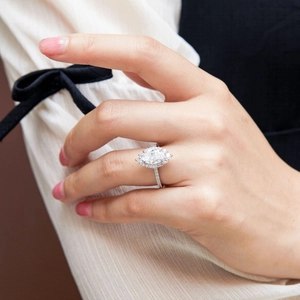 Close-up of a marquise-cut zircon halo ring on a finger with elegant sleeve detail