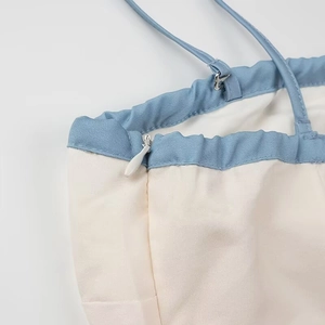 Detail shot of invisible zipper and seam stitching on light blue and cream strap dress