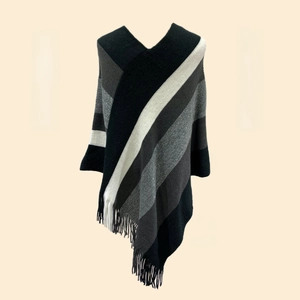 Detailed view of women's knitted poncho featuring gray striped patterns and fringe trim