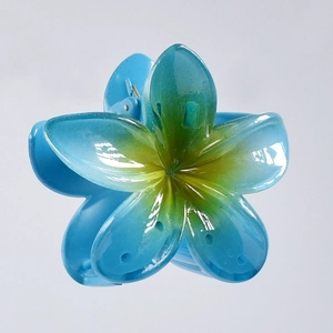 Detail of blue resin plumeria hair claw clip with yellow gradient center and glossy finish