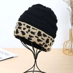 Women's winter knit beanie with black crown and leopard print cuff on a display stand